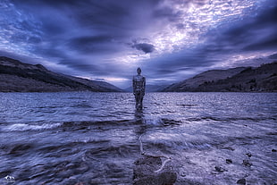 person standing on body of water under cloudy sky