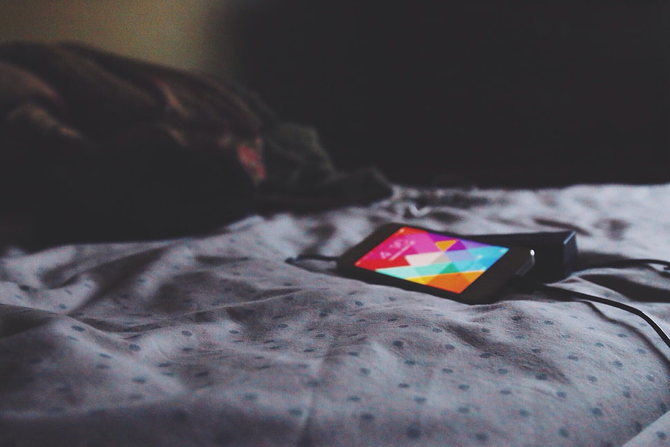 black android smartphone on top of white bedsheet HD wallpaper