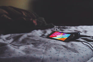 black android smartphone on top of white bedsheet