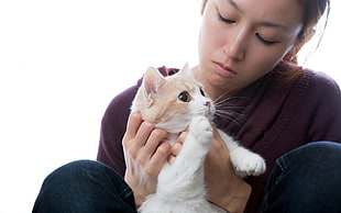 woman holds white and orange cat