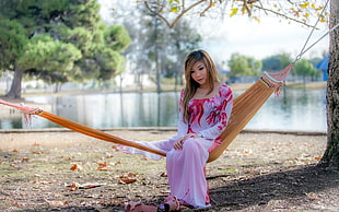 woman in white and red floral long-sleeved dress sitting on brown hammock during daytime HD wallpaper