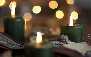 selective focus photography of lighted green pillar candle with bokeh light background