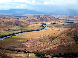birds-eye view photography of river in between brown hills