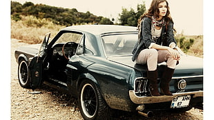 woman sitting in black Ford Mustang Fastback