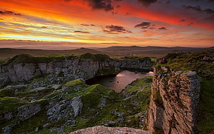 rock formation near body of water during sunset