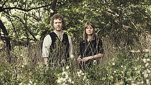 woman and man standing behind brown grass HD wallpaper
