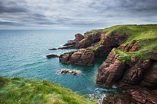 photo of brown rock formations beside sea during daytime, seaton