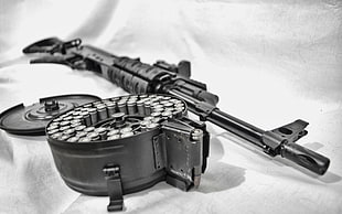 black assault rifle with rotating magazine on white textile