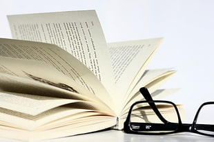 open page book beside black frame eyeglasses