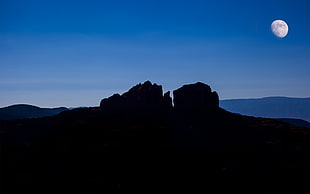 rock formation and moon during dawn time