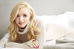 woman in brown sweater lying on bed taking a pose for a picture