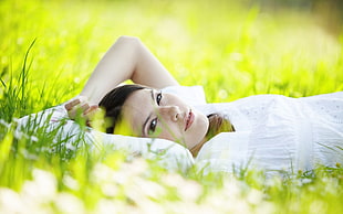 woman in white shirt lying on grass during day time