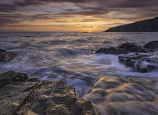 photo of sea waves and rock formation during golden hours, porth