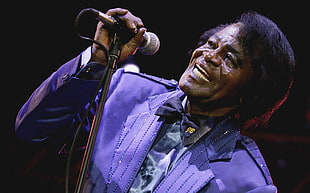 man wearing purple coat while singing
