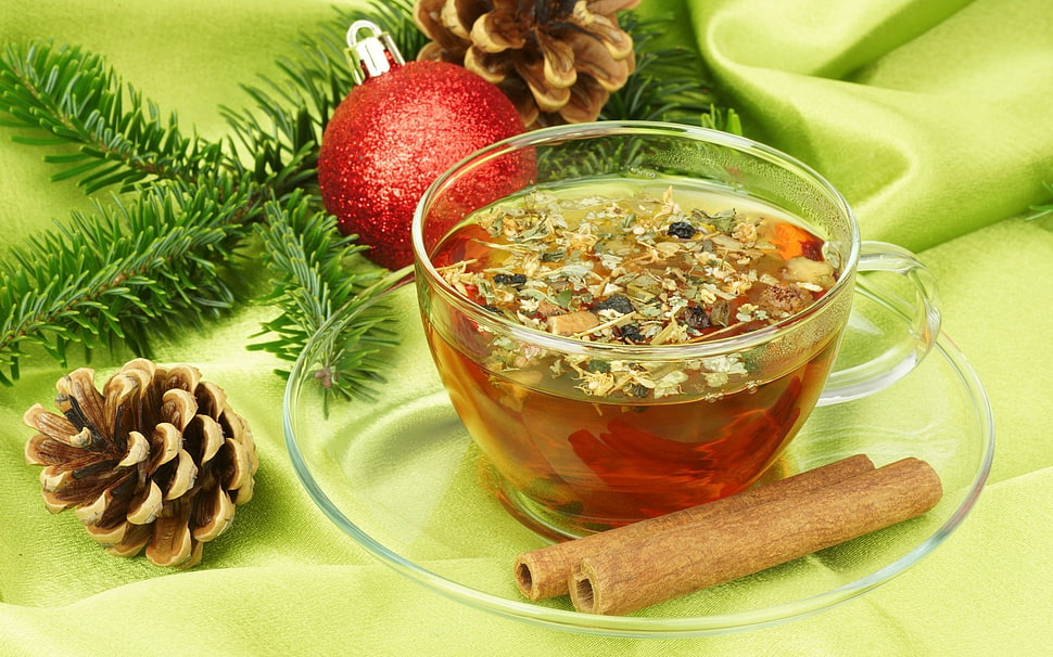 clear glass teacup filled with tea beside two baked sticks HD wallpaper
