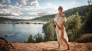 standing woman wearing white off-shoulder dress on near cliff at daytime