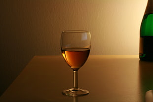 clear wine glass with liquid inside on table HD wallpaper