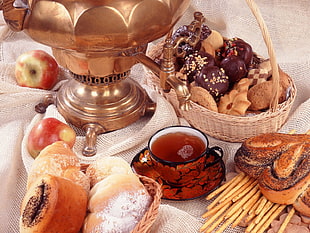 assorted breads in brown wicker basket near filled floral teacup with saucer