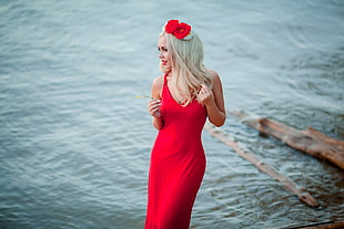 woman wearing red sleeveless dress beside body of water