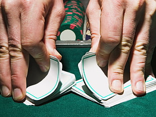 person flipping game cards on green table