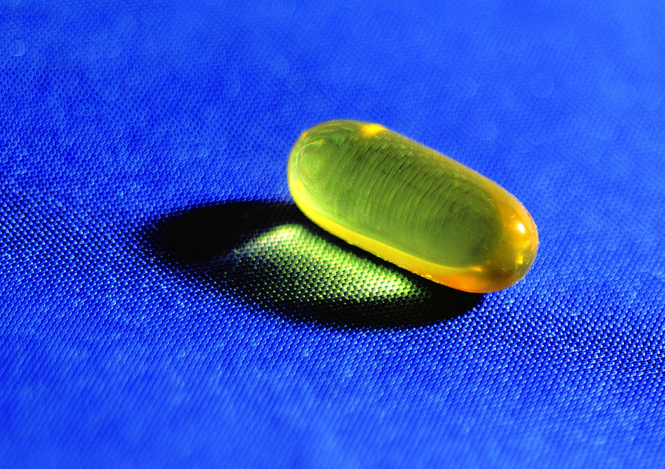 clear yellow medication pill in closeup photography HD wallpaper
