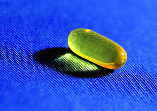 clear yellow medication pill in closeup photography