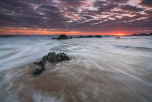 time-lapse photography of body of water and rocks under gay sky, porth, tywyn