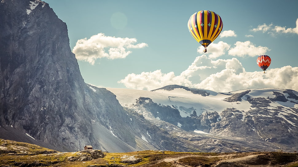 two hot air balloons on flight nearby mountain HD wallpaper