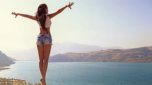 woman wearing blue hot shorts standing on rock cliff