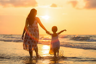 woman and girl on sea water golden hour