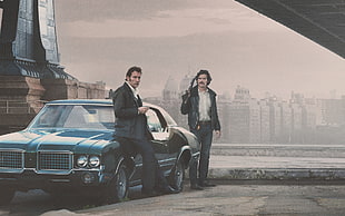 photo of two men standing beside blue coupe