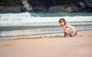 toddler wearing yellow and white dress on seashore
