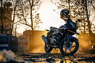black naked motorcycle parked on black pavement during golden hour