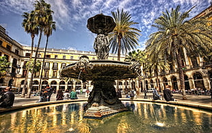 woman holding umbrella statue on outdoor water fountain surround with buildings