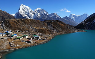 brown and white mountains along side green lake