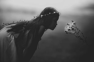 grayscale photography of girl looking at a dandelion flower