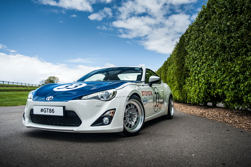 white and blue Toyota coupe beside green leaf wall HD wallpaper