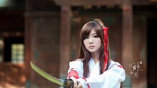 woman wearing white and red long-sleeved top holding katana at daytime