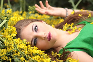 women's green sleeveless dress lying on yellow flowers