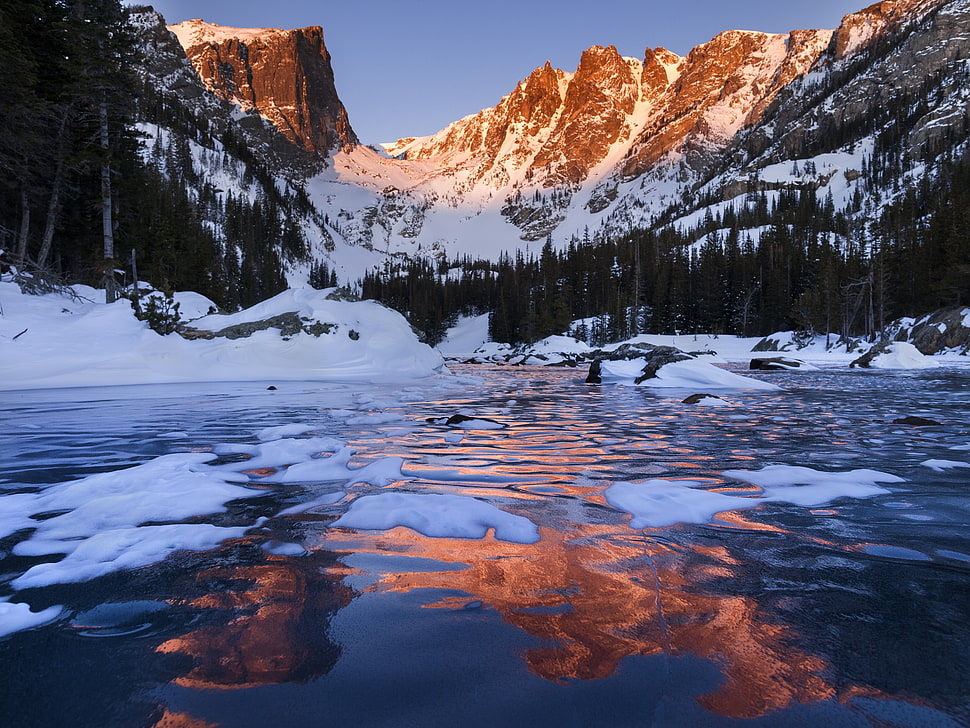 brown mountain covered by snow near body of water HD wallpaper