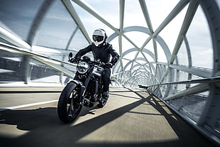 photo of person riding on gray and black cruiser motorcycle on clear glass tunnel