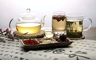 glass tea set beside chips and chocolate on white and gray tablet cloth