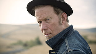 depth of field photography of man in blue denim jacket and black cap