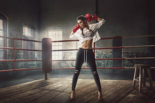 photo of woman wearing red punching gloves and black sweatpants standing inside ring