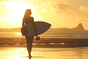Woman Holding Surf Board Standing on Shoreline during Sunset HD wallpaper