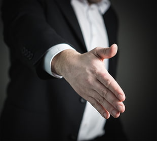 photo of person wearing tuxedo suit shaking left hand