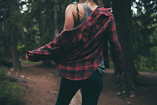 woman in red and black plaid dress shirt standing on forest during day time