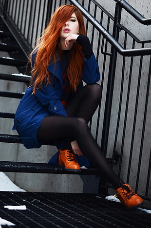 woman wearing blue overcoat sitting on the stairs