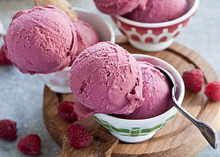 strawberry flavored ice creams on white ceramic bowls with stainless steel spoon