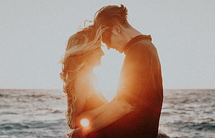 couple hugging near ocean during golden hour